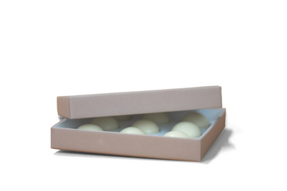 An open box of floral scent massage oil pearls by Masmoi, arranged in a minimalist beige packaging. 